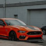 Luxury Cars - A striking orange sports car parked outdoors sho #10905516