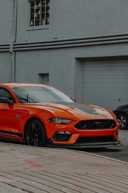 Luxury Cars - A striking orange sports car parked outdoors sho #10905516
